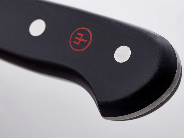 Close-up of a knife blade with a visible brand logo on a light gray background