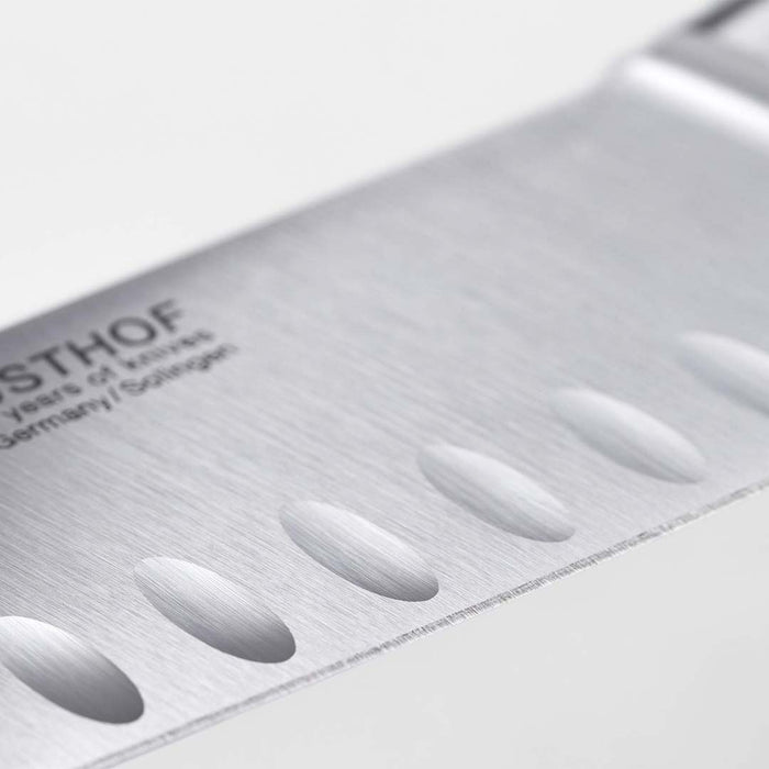 Close up of the blade of Wusthof Ikon blackwood hollow edge santoku knife on a white background
