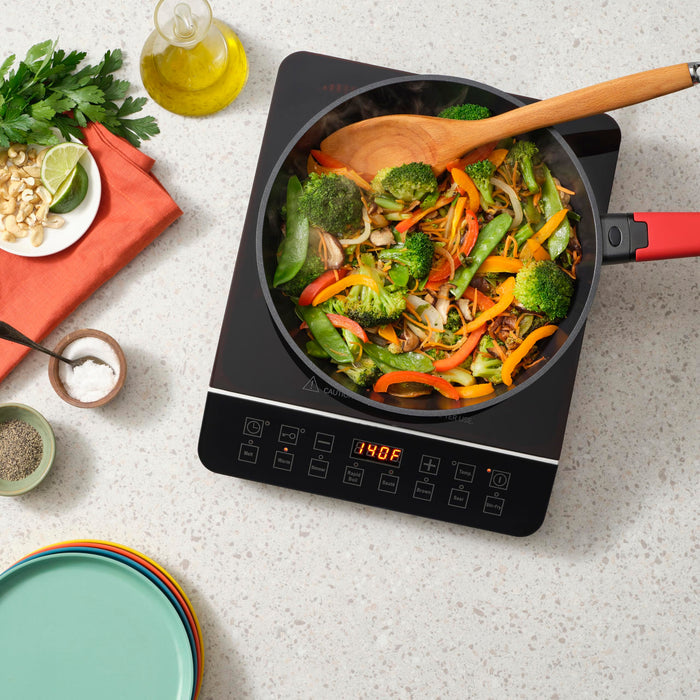 Zavor onyx induction cooktop with stir fry within a skillet on a countertop with prepped ingredients